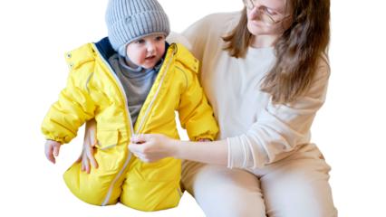 Child is dressed in warm winter clothes for a walk outside, isolated on white background. Woman mother puts clothes on toddler baby boy for cold weather. Kid age one year five months