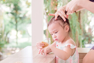 Mother is combing daughter's hair. Baby hair tied with colorful rubber bands in two funny...