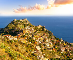 scenic view from highland to a mountain town with beautiful buildings, castles, hills and slopes and panoramic sea gulf with cloudy sky on background