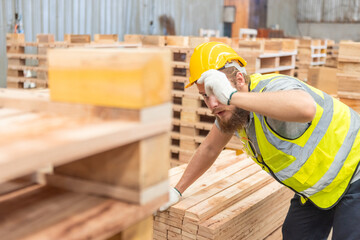 Man wearing safety uniform and yellow hard hat working checking quality wooden products at workshop...