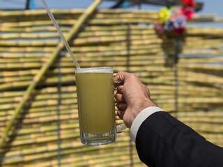 Man is holding a sugar cane juice glass in his hands in hot summary day. Pakistan Street drink.