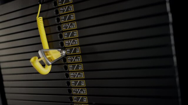 A person is seen adjusting weights on a weight machine in the gym, using a screwdriver for adjustments. Closeup shots of the stack of weights are shown