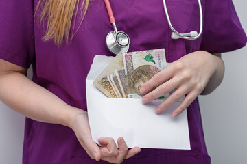 Pani doktor trzyma w dłoniach kopertę z pieniędzmi  - obrazy, fototapety, plakaty
