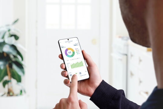 Guy monitors home electricity usage with smart home app. Concept of energy efficiency, technology, and household management for sustainable living