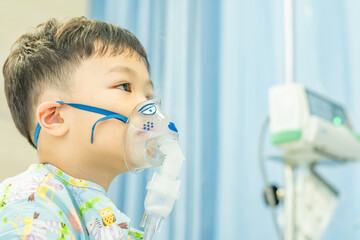 Little asian boy making inhalation with nebulizer at hospital. Decreasing resistance in the respiratory airway and increasing airflow to the lungs. The boy is getting bronchodilator. Copy space.