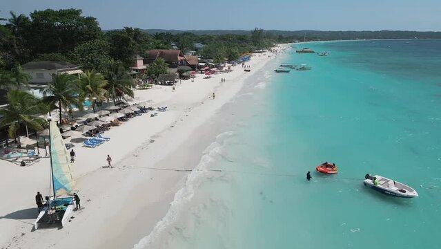Aerial video above vacationing people and boats on jamaica coastline