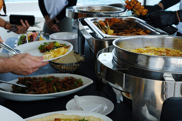 Attentive Service at Yacht Buffet in Dubai. A buffet on a yacht in Dubai with a service attendant carefully plating food for a memorable dining experience