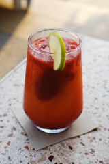 Icy Fruit Mocktail Ready to Enjoy Poolside. An icy non-alcoholic fruit mocktail topped with a slice of lime. Vertical photo