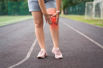 Diseases of the knee joint, bone fracture and inflammation, athletic woman on a running track after workout suffering from pain in leg and doing self-massage - 754200372