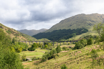 Fototapeta na wymiar The Glenfinnan Viaduct arches gracefully over the lush Scottish countryside, embraced by rolling green hills