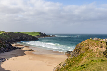 The tranquil beauty of Scotland's Durness Beach is captured in this image, featuring a secluded sandy bay bordered by emerald cliffs and the crystal-clear waters of the Atlantic