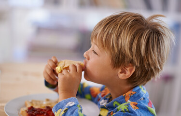 Food, breakfast and boy eating a sandwich in morning, pyjamas and home for nutrition. Children,...