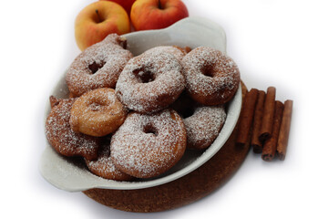 Deep fried apple rings with batter sprinkled with powdered sugar an cinnamon on white background