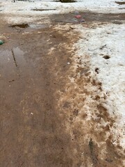 Melting dirty snow on the streets of the city during the daytime in winter. Snow with sand and mud lies on the road