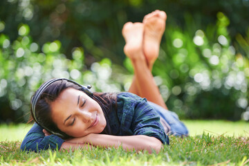 Grass, park and woman with headphones, listening to music and streaming audio with peace, relaxing or summer. Person in a garden, outdoor or girl with headset or podcast with radio, sunshine or sound