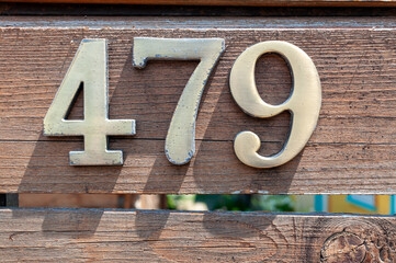 House number plate 479 on a wooden fence. Street number. Address number.