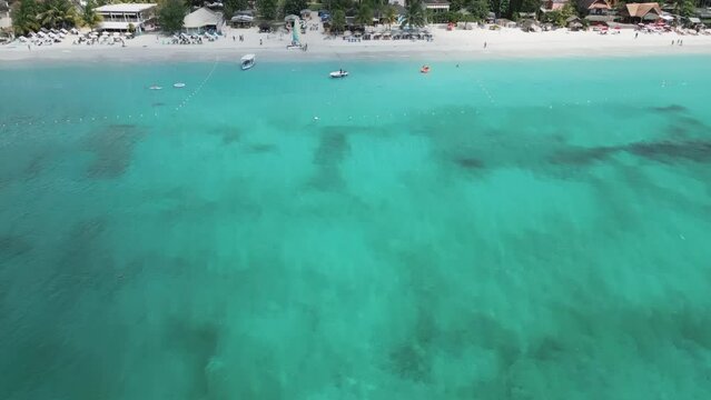 Aerial video above vacationing people and boats on jamaica coastline