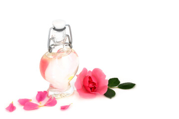 Rosewater with pink rose flower with heart shaped bottle. Natural healthy skincare to hydrate skin, reduce redness, irritation, treat scars, burns, restores ph balance. On white background.