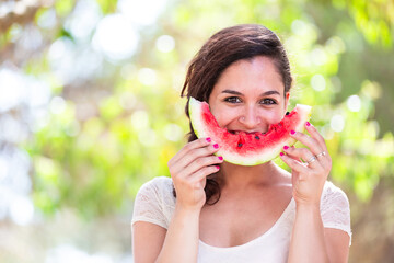 Beautiful young woman at park eating a slice of watermelon - 754221373