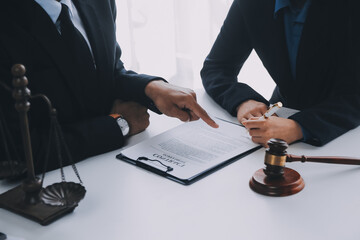 Justice and Law concept. Legal counsel presents to the client a signed contract with gavel and legal law or legal having team meeting at law firm in background