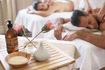 Poster Salon de massage Hotel, flowers and couple in spa to relax on bed or break with luxury pamper treatment tools on table. Protea, facial oil or woman with man at resort or salon for natural healing benefits or massage