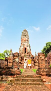 people are gathered outside an ancient brick building, surrounded by lush trees and a picturesque sky. This historic site is rich in history and archaeological significance Ayutthaya, Thailand