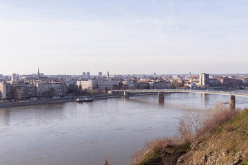 Fototapeta na wymiar Cityscape of Novi Sad, bridge over Danube river. Panoramic view. Downtown at riverside. Cloudy spring day at noon. Serbia. Europe. 