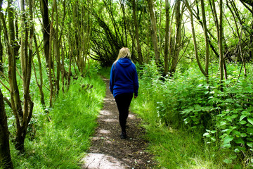 A single woman walking through the countryside on a beautiful summer afternoon