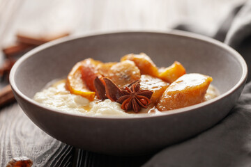 Sweet milky semolina porridge with caramelised apples and bananas in a bowl on the table. Healthy children's breakfast