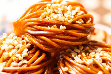 A plate of Chebakia with almonds, a traditional Moroccan pastry. These golden-brown delights are intricately shaped, coated in honey, and adorned with almonds, offering a delightful blend of sweetness