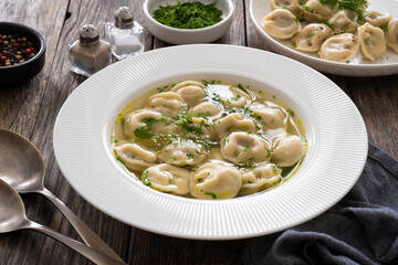 Pelmeni - dumplings filled minced meat in broth on wooden table
