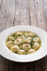 Pelmeni - dumplings filled minced meat in broth on wooden table
