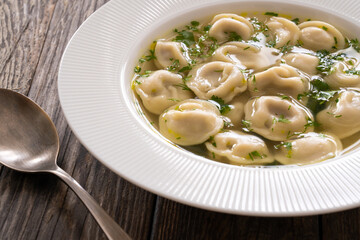 Pelmeni - dumplings filled minced meat in broth on wooden table
