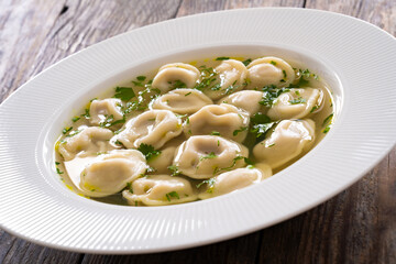 Pelmeni - dumplings filled minced meat in broth on wooden table
