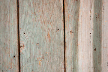 Green painted wooden wall with nails hammered in and paint peeling off in places