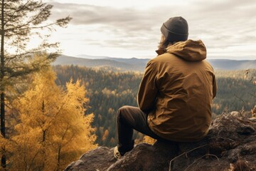 A man sitting on a rock, enjoying the view. Suitable for travel brochures