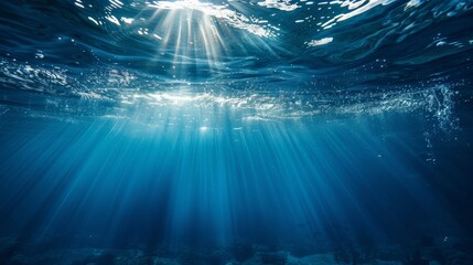 Underwater view with sunbeams shining through the ocean's surface, creating a serene and ethereal blue world. - obrazy, fototapety, plakaty