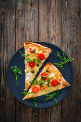 Roman pinsa slices with mozzarella cheese, capers, arugula and garlic on wooden table

