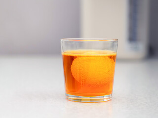 A glass with orange dye for an easter egg. An egg in a glass. Preparation for the Easter holiday.