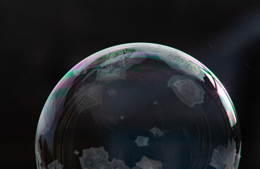 Winter collage. A transparent soap bubble freezing in the cold on a dark background. Tom 3