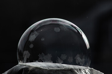 Winter collage. A transparent soap bubble freezing in the cold on a dark background. Tom 7