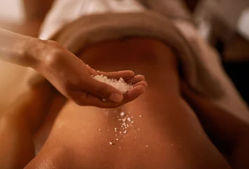 Poster Hand, back and salt at spa for massage, skin care and wellness for luxury, holistic therapy and peace. Grain, exfoliate and health for lifestyle, body and person on table, calm and natural © Tasneem/peopleimages.com