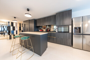 an image of a newly fitted luxury kitchen with black cabinet doors and island bar with stools in...