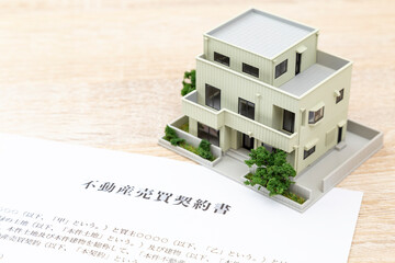 机に住宅模型と契約書