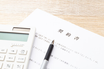 机に置かれた契約書と電卓