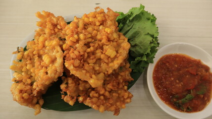 Crispy fried corn balls in white plate on wooden table, vegetarian food.