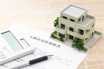 机に住宅模型と契約書