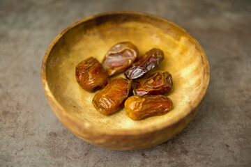 Dried dates fruits in wooden bowl isolated, ramadhan fruits.