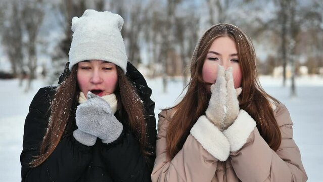 Two young freezing friends shivering on a winter's day.
