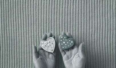 Hands Holding Decorative Heart-Shaped Objects on Textured Background